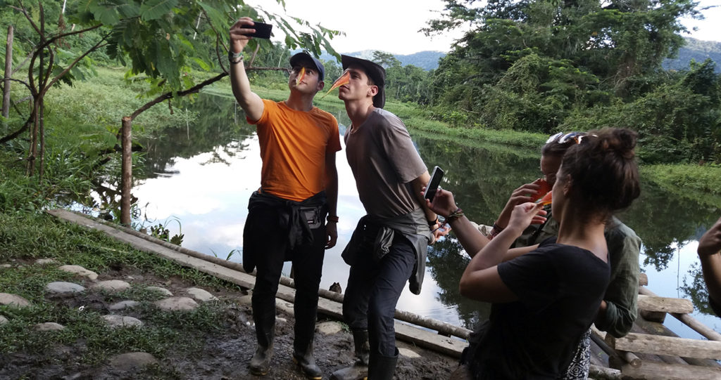 Viajeros tomándose selfis a orillas de una cocha en el Manu