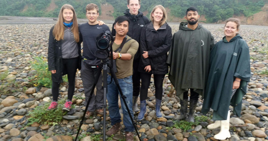 Percy Huanca and a group of travelers with a spotting scope on a river beach