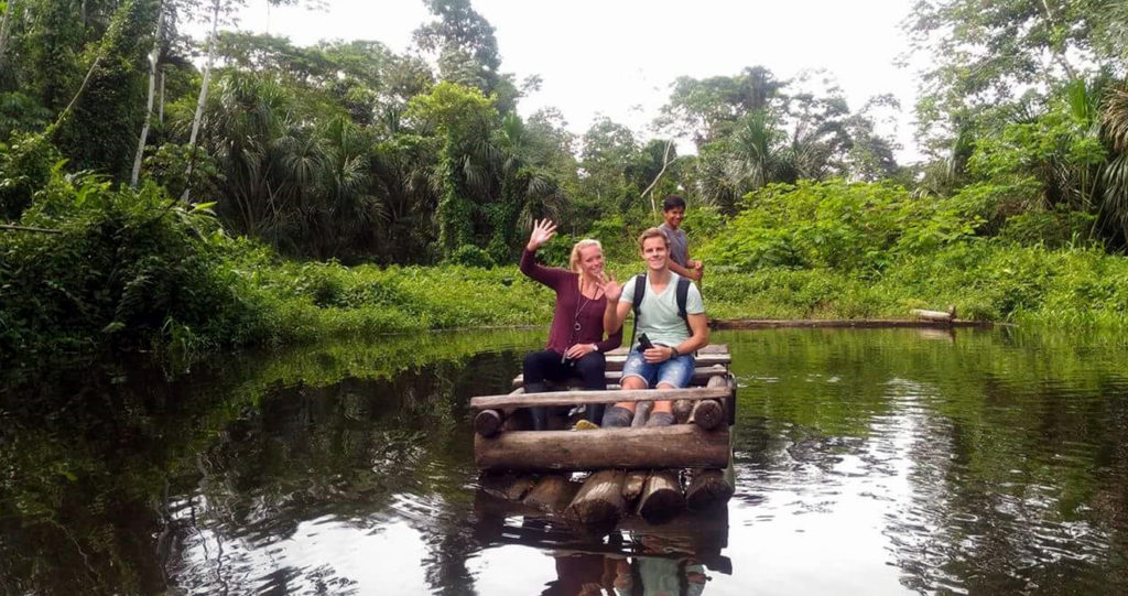 Travelers waving from a wooden raft on an oxbow lake