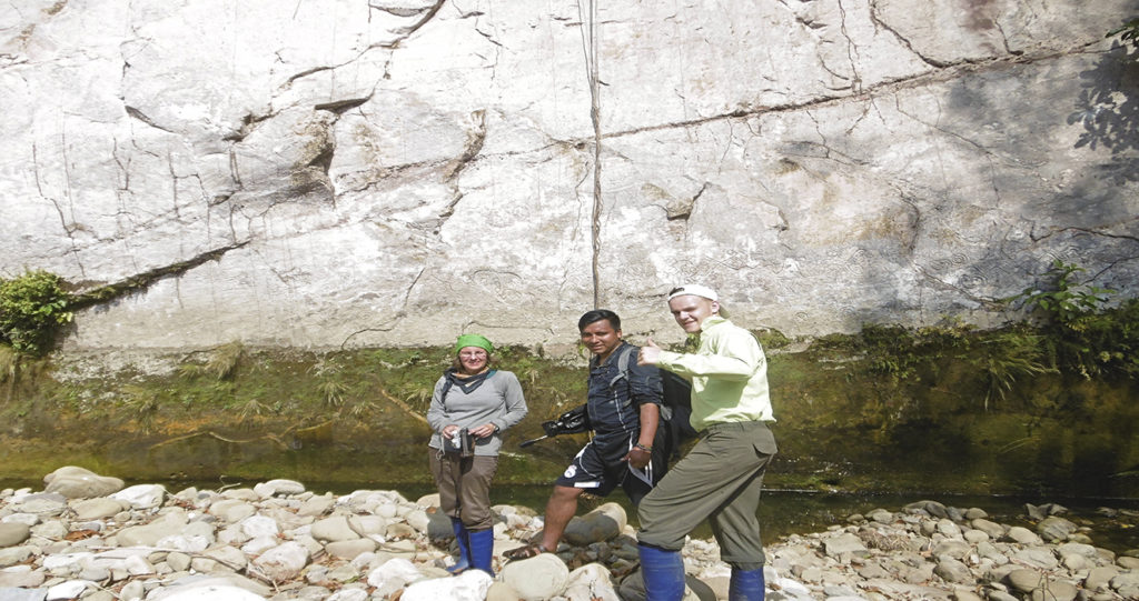 Percy Huanca and travelers at the foot of the Pusharo petroglyph wall