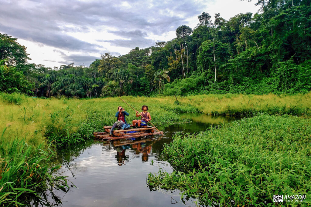 Two travelers on a wooden raft at the Machuhuasi oxbow lake