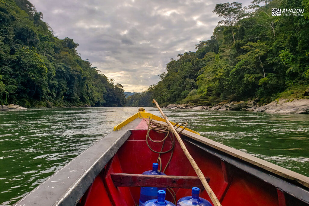 Bow of a wooden boat on a river between forested hills